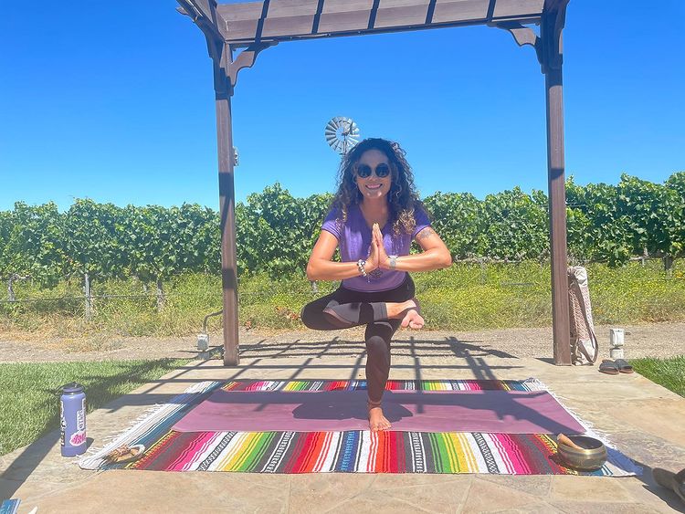 Jenn in a yoga pose under the vineyard pergola